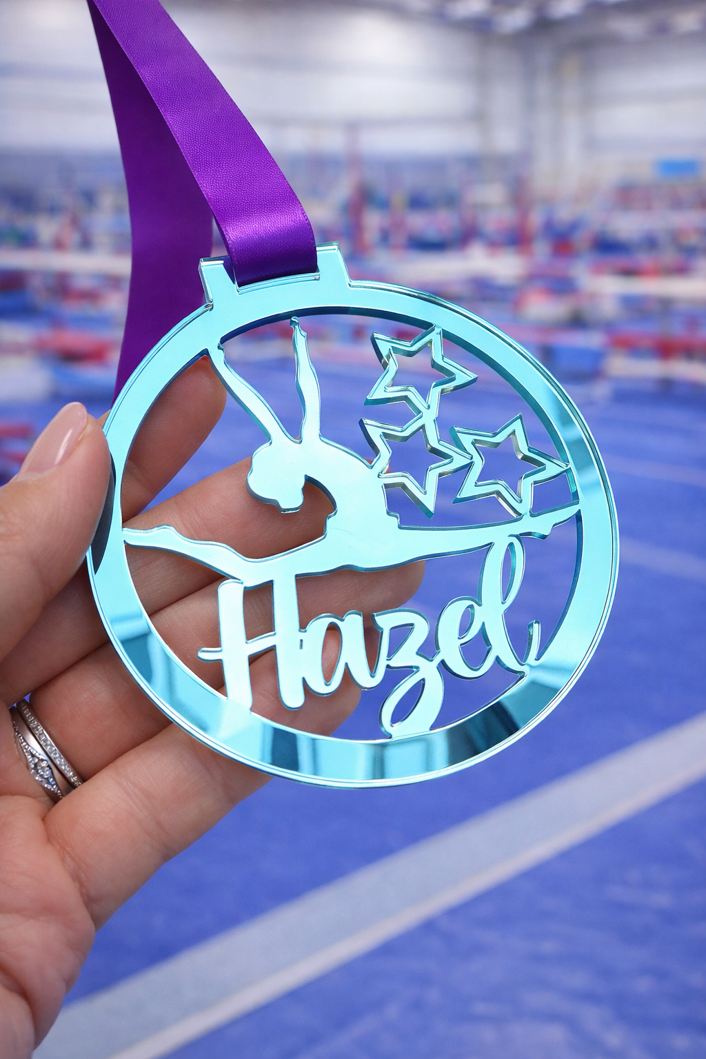 blue mirror acrylic personalised gymnastics medal held in hand with custom name design